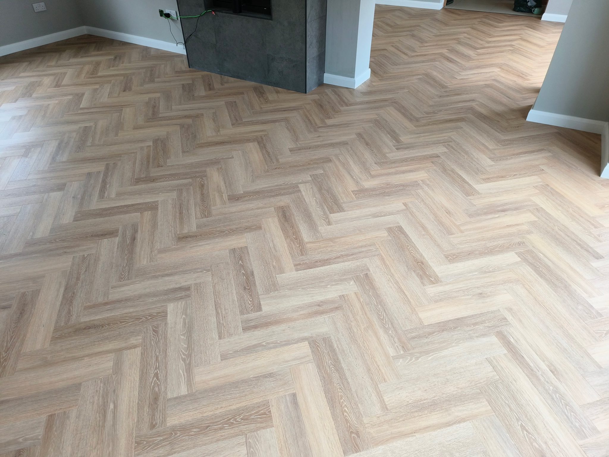 Image of a room with Herringbone Luxury Vinyl Tile (LVT) flooring. The tiles have a natural oak appearance, offering a classic and elegant wood look with the durability and ease of maintenance of vinyl.